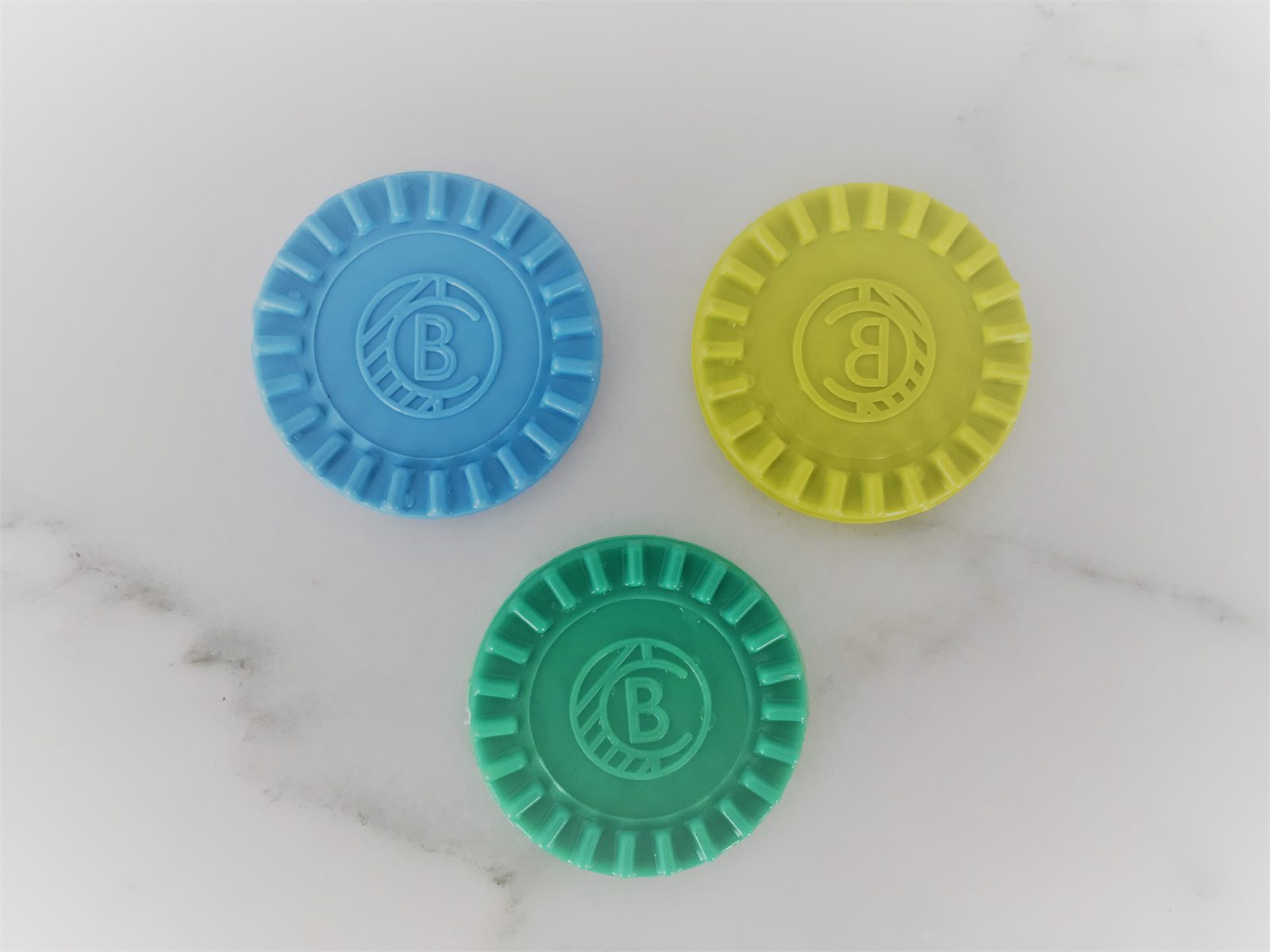 Injection-molded BC monogram coins in blue, yellow, and green